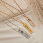 Close-up of a pendant necklaces featuring an engraved birth flower with a personalized name as the stem.