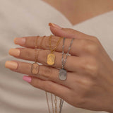 Close up of women hand holding three necklaces of different dog breeds ear outline in rose gold, gold and silver