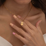 Close-up of a gold pendant necklace engraved with a dog's ear outline, worn by a woman.