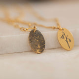 Close-up of a gold pendant engraved with a fingerprint on the front, customizable with a birth flower on the back.
