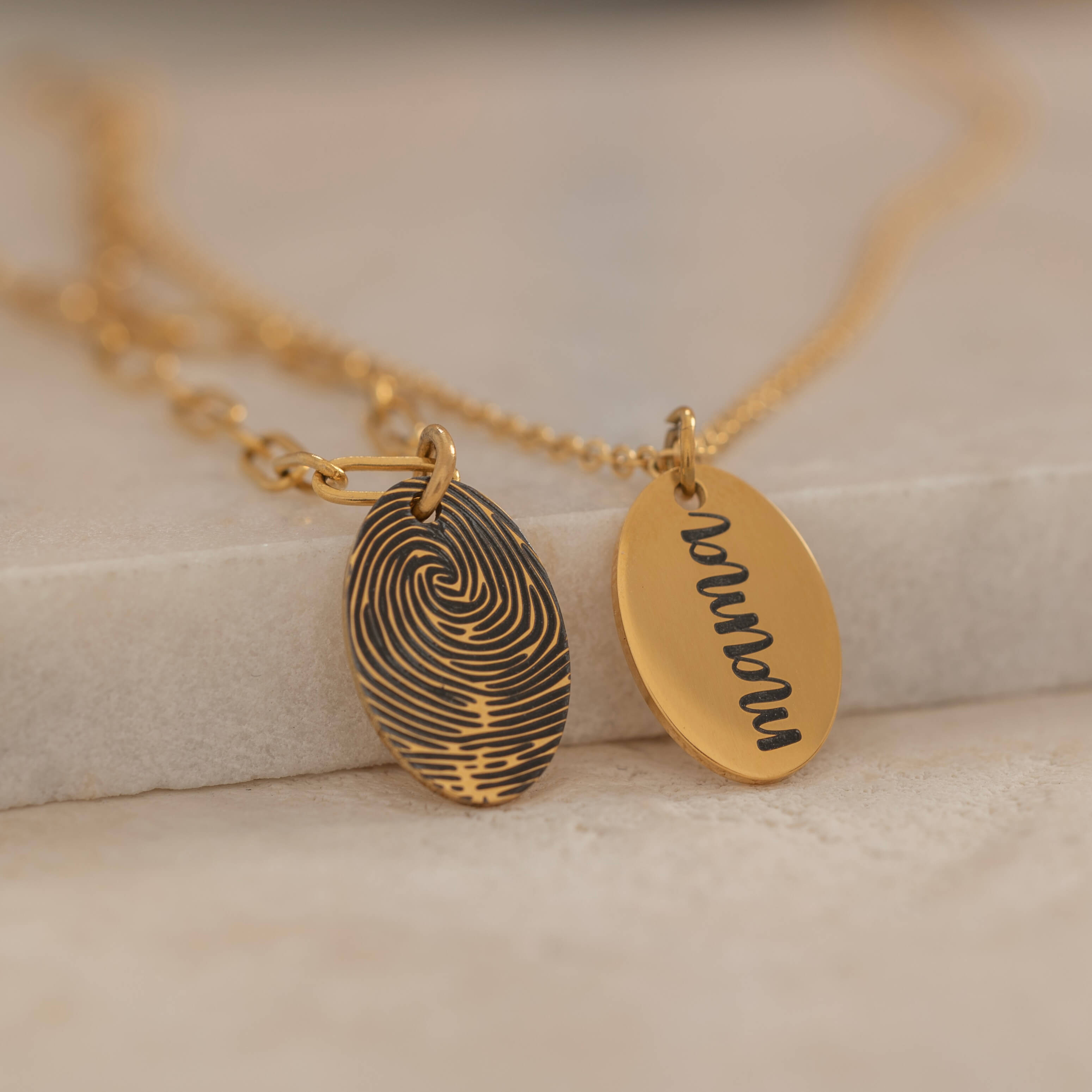 Close-up of a gold pendant engraved with a fingerprint on the front, customizable with a text on the back.