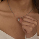 Close-up of a silver pendant necklace featuring an engraved outline of the state of Florida worn by a woman.