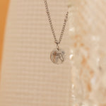 Close-up of a silver pendant necklace featuring an engraved outline of the state of Florida. 