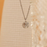Close-up of a silver pendant necklace featuring an engraved outline of the state of Florida. 