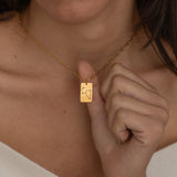 Close-up of a constellation necklace pendant worn by a woman, showcasing a minimalist engraved star pattern.