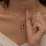 Gold and silver rectangular pendants with tiger engravings, featuring a sparkling cubic zirconia accent. They symbolize the strength tarot necklace. Available in both gold-plated and sterling silver chains.