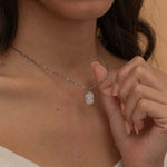 Close-up of a silver pendant necklace engraved with a dog's ear outline, worn by a woman.