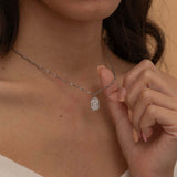 Close-up of a silver pendant necklace engraved with a dog's ear outline, worn by a woman.
