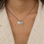 Silver necklace with multiple charms, each engraved with different US state outlines and personalized message, worn by a woman.