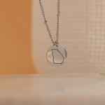 Silver necklace of a US State outline hanging 