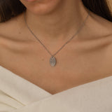 Close-up of a silver pendant necklace engraved with a personalized fingerprint, worn by a woman.