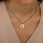 Silver pendant necklace featuring an engraved portrait of a horse worn by a woman
