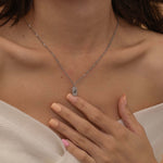 Close-up of a silver pendant necklace engraved with the letter "A," worn by a woman.