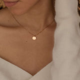 Close-up of a rose gold pendant necklace featuring an engraved outline of a state worn by a woman.