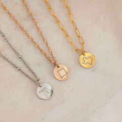 Close up of three necklace with US states outlines in gold, silver and rose gold 