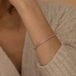 Close-up of a gold tennis bracelet with sparkling pink stones, perfect for adding a touch of color to any outfit.