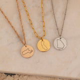 Three Necklaces of US states gold, silver and rose gold on top of a stone