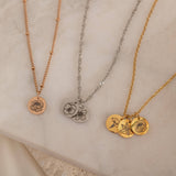 Close-up of three custom birth flower engraved pendant necklace on a decorative stone, showcasing birth flowers