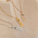 Close-up of a pendant necklaces featuring an engraved birth flower with a personalized name as the stem.