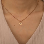 Close-up of a rose gold custom birth flower engraved pendant necklace worn by a woman, showcasing one round charms with floral engravings.