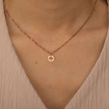 Close-up of a rose gold custom birth flower engraved pendant necklace worn by a woman, showcasing one round charms with floral engravings.