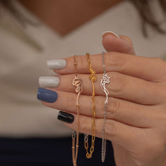 Gold, silver, and rose gold birth flower bracelets with delicate floral outlines on different chain styles.