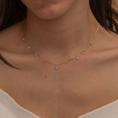 Dainty sterling silver and 14k gold plated necklace featuring four square opal birthstone stones, one centered teardrop-shaped opal stone, and four white cubic zirconia accents between the opal birthstones. Perfect for mother’s day and prom. 