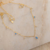 Dainty sterling silver and 14k gold plated necklace featuring four square blue zircon stones, one centered teardrop-shaped blue zircon stone, and four white cubic zirconia accents between the December birthstones.