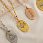 Close-up of a gold, silver and rose gold pendant necklaces featuring each a personalized engraving of a plant leaf design.