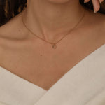 custom initial charm necklaces in gold, silver, and rose gold finishes, each with distinct chain styles and personalized round charms on a marble surface.