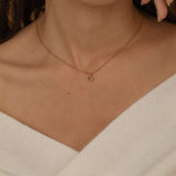 custom initial charm necklaces in gold, silver, and rose gold finishes, each with distinct chain styles and personalized round charms on a marble surface.