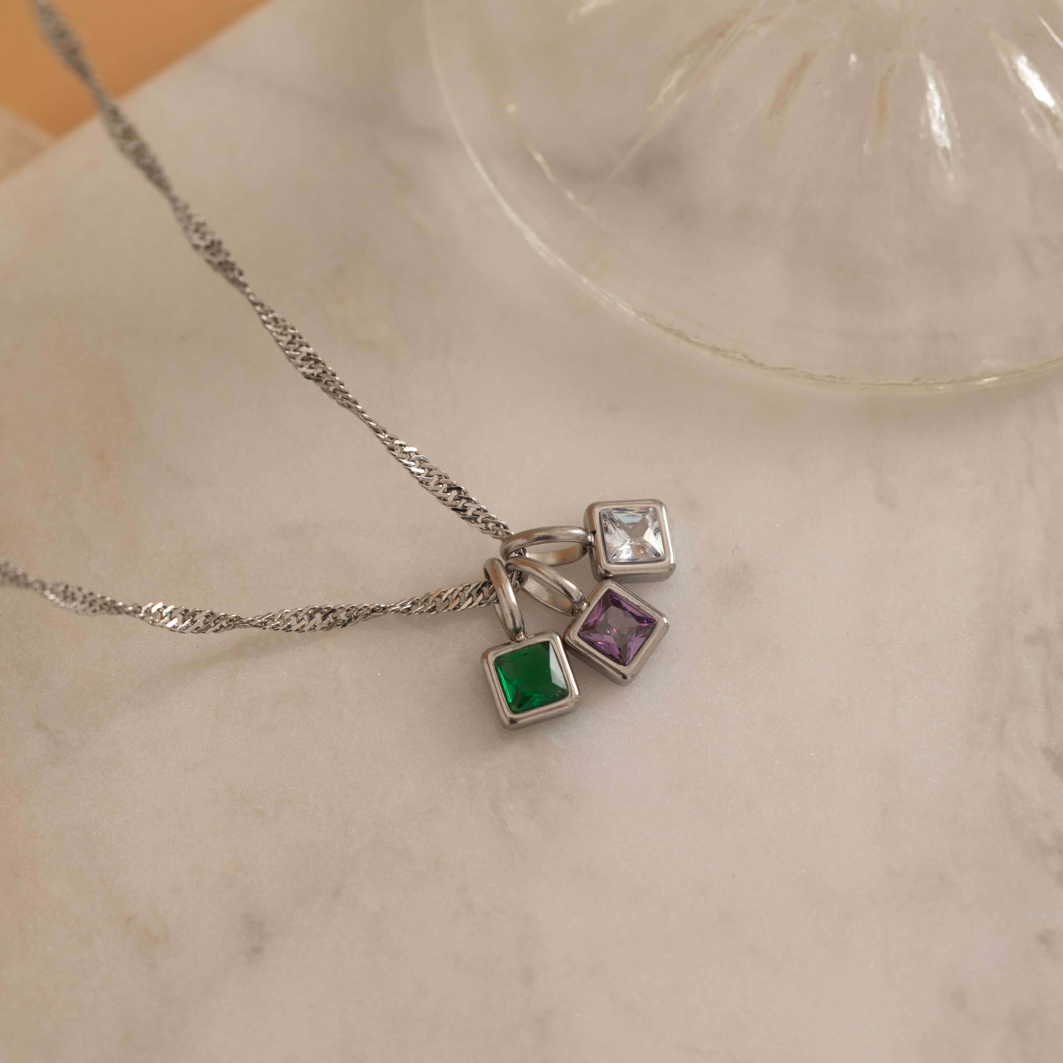Square birthstone charms in gold and silver frames on a necklace, with multiple colorful birthstone charms representing different birth months