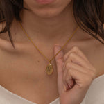 Gold zodiac pendant necklace on a dainty elongated rope chain, featuring an engraved oval charm available in all zodiac signs for personalized style.