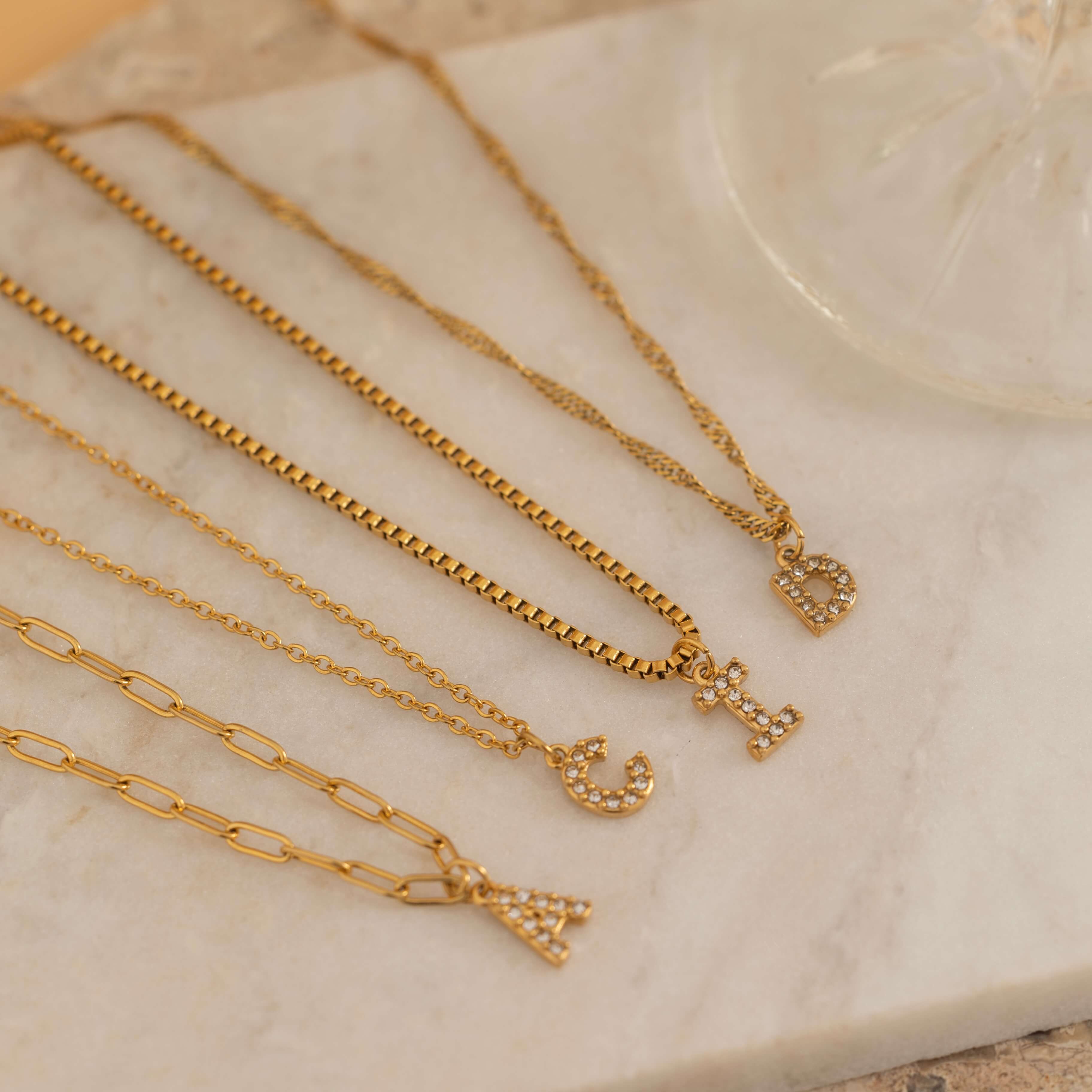 Gold initial pendant necklaces with crystal-studded alphabet charms on custom gold chains