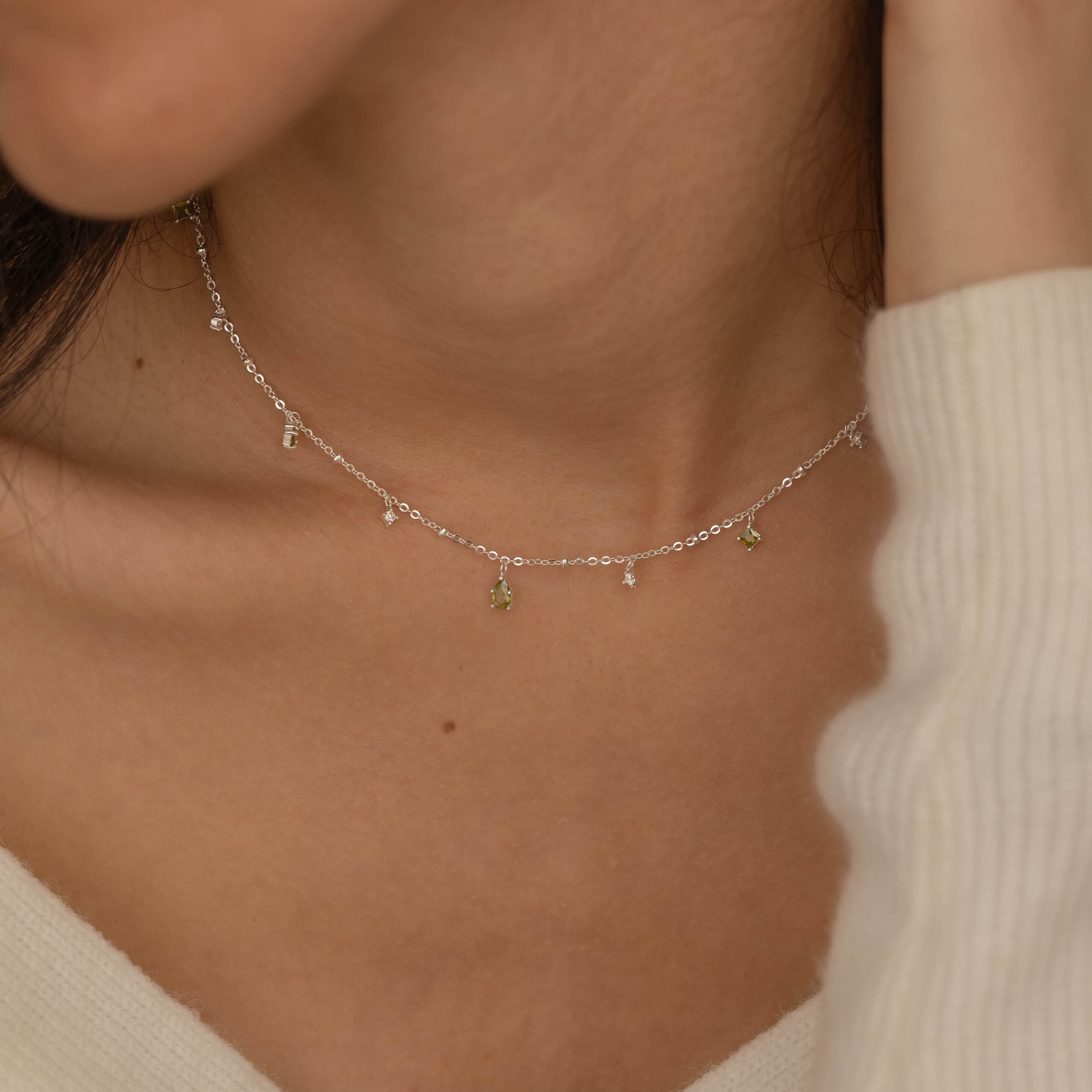 Dainty sterling silver necklace featuring four square peridot-colored cubic zirconia stones, one centered teardrop-shaped peridot stone, and four white cubic zirconia accents between the peridot.
