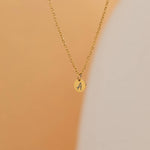 custom initial charm necklaces in gold, silver, and rose gold finishes, each with distinct chain styles and personalized round charms on a marble surface.