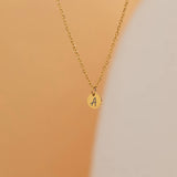 custom initial charm necklaces in gold, silver, and rose gold finishes, each with distinct chain styles and personalized round charms on a marble surface.