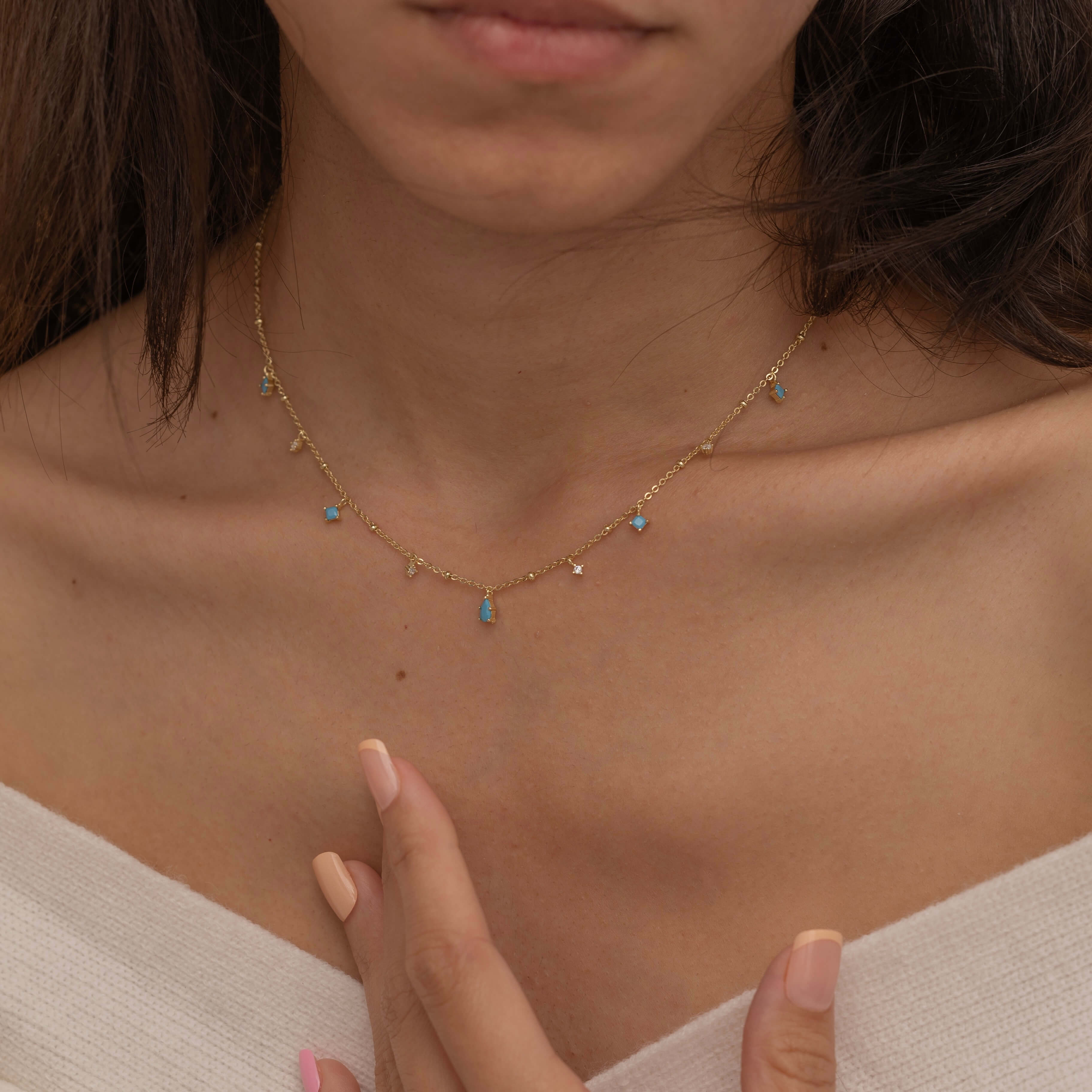 Dainty sterling silver and 14k gold plated necklace featuring four square turquoise birthstone stones, one centered teardrop-shaped turquoise stone, and four white cubic zirconia accents between the turquoise stones. Perfect for mother’s day and prom. 