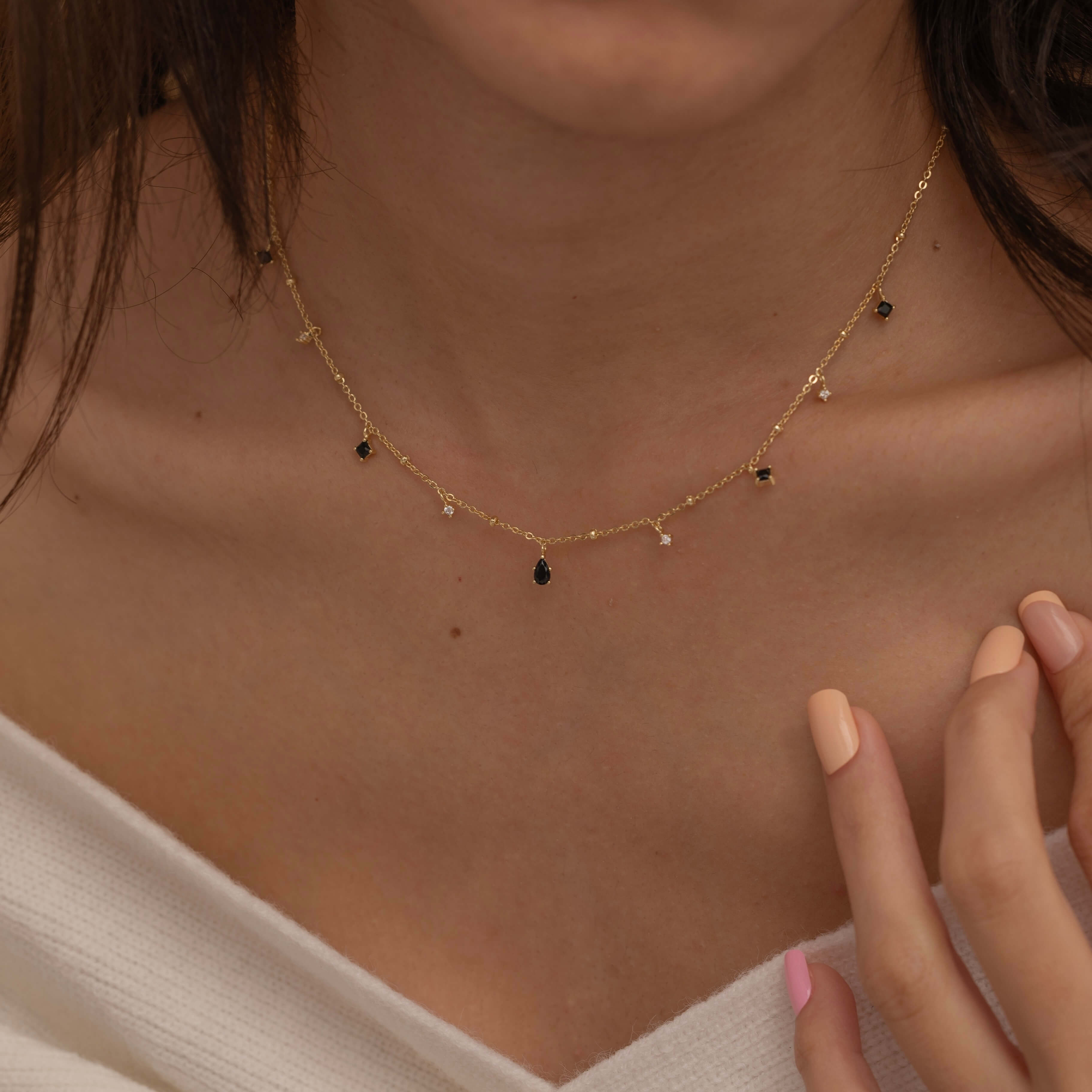 Dainty sterling silver and 14k gold plated necklace featuring four square black onyx birthstone stones, one centered teardrop-shaped onyx stone, and four white cubic zirconia accents between the onyx stones. Perfect for mother’s day and prom. 