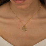 Close-up of a gold pendant necklace engraved with a personalized fingerprint, worn by a woman.