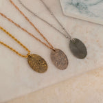 Close-up of three necklaces engraved with a personalized fingerprint, on top of a stone