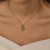 Close-up of a rose gold pendant necklace engraved with a personalized fingerprint, worn by a woman.