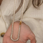 Elegant gold tennis necklace with a continuous row of sparkling, rectangular-cut stones. Perfectly aligned gemstones create a seamless shimmer, adding timeless sophistication to any look. Classic luxury jewelry piece ideal for formal occasions or adding everyday elegance.