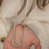 Elegant gold tennis necklace with a continuous row of sparkling, rectangular-cut stones. Perfectly aligned gemstones create a seamless shimmer, adding timeless sophistication to any look. Classic luxury jewelry piece ideal for formal occasions or adding everyday elegance.