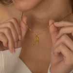 Close-up of a gold pendant necklace engraved with a personalized fingerprint, worn by a woman.