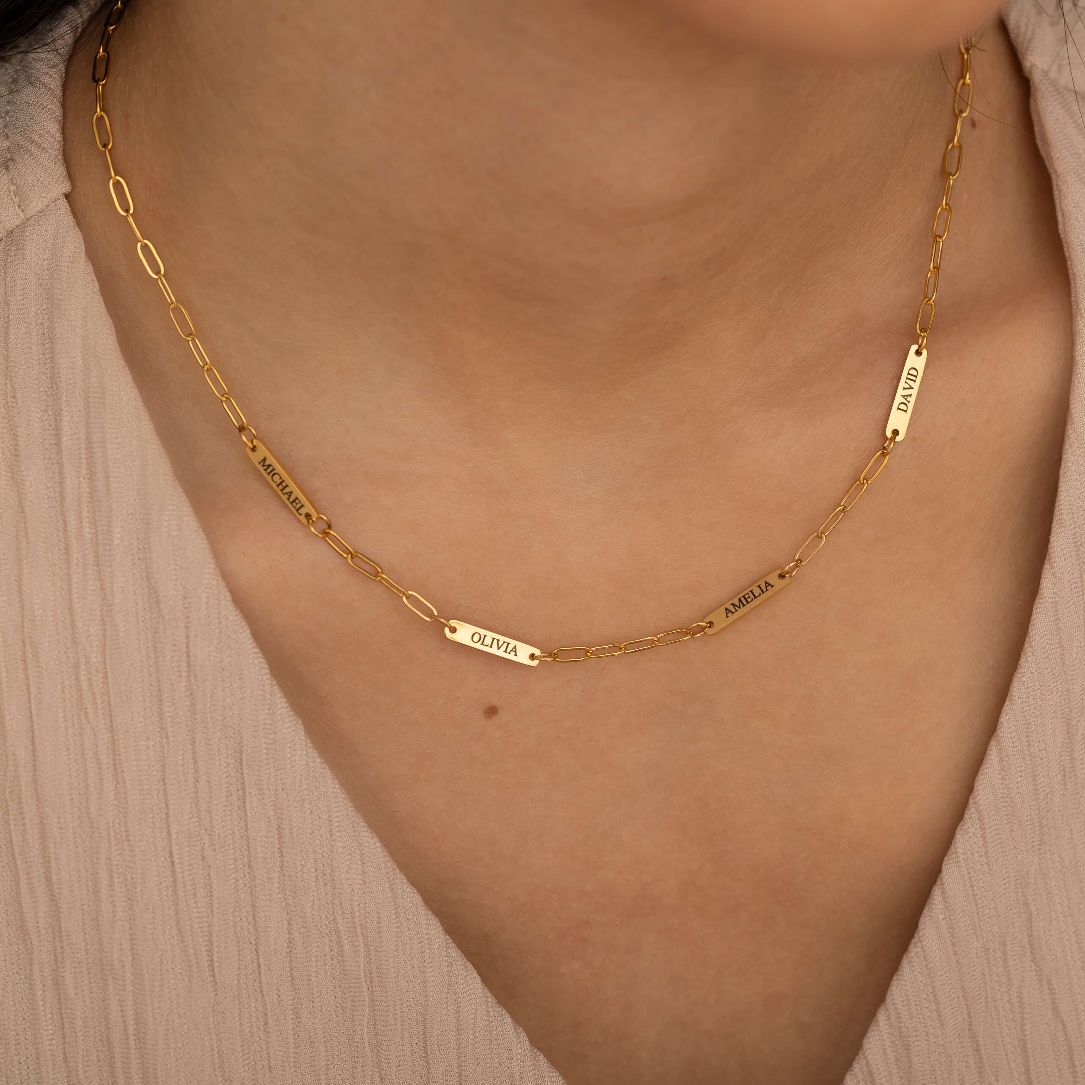 Gold necklace with multiple engraved name bar charms, personalized family name jewelry
