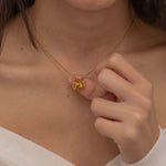 Close-up of a gold necklace with multiple engraved pendants, each featuring different initials, worn by a woman.