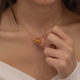 Close-up of a gold necklace with multiple engraved pendants, each featuring different initials, worn by a woman.