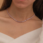 Elegant gold tennis necklace with a continuous row of sparkling, rectangular-cut stones. Perfectly aligned pink gemstones create a seamless shimmer, adding timeless sophistication to any look. Classic luxury jewelry piece ideal for formal occasions or adding everyday elegance.