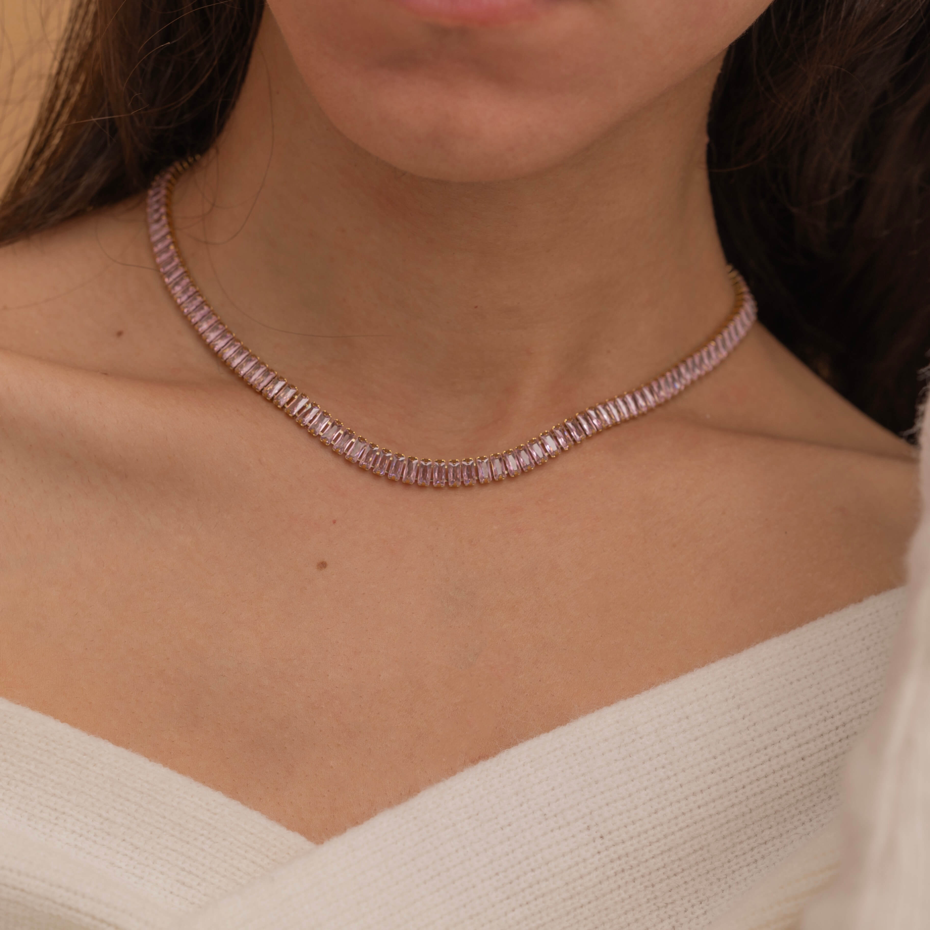 Elegant gold tennis necklace with a continuous row of sparkling, rectangular-cut stones. Perfectly aligned pink gemstones create a seamless shimmer, adding timeless sophistication to any look. Classic luxury jewelry piece ideal for formal occasions or adding everyday elegance.